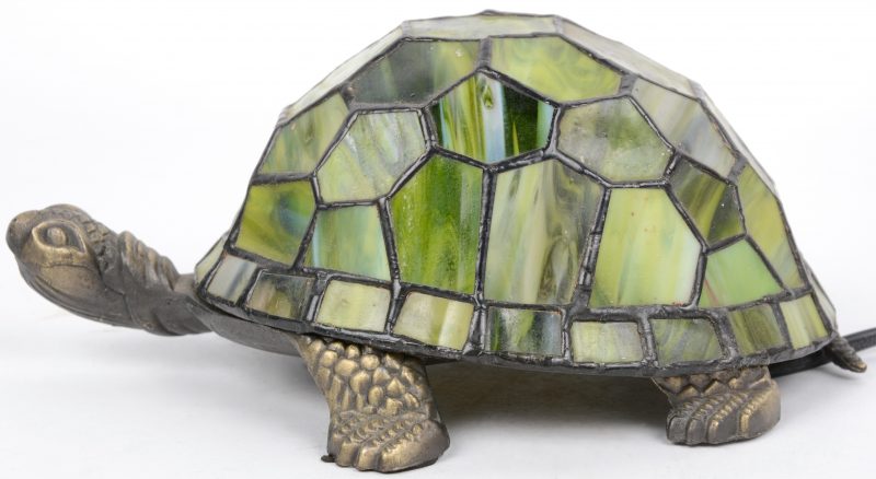 Een lampje van gebronzeerd koper met een kap van glas in lood in de vorm van een schldpad.