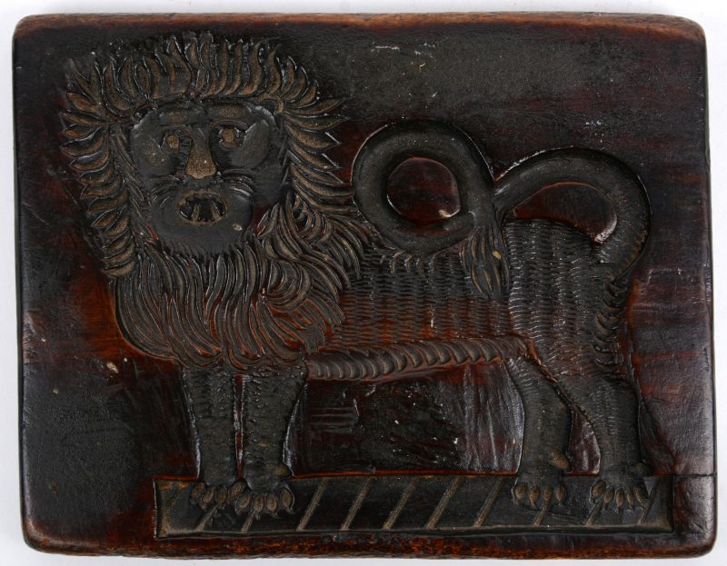 Een oude speculaasplank in de vorm van een leeuw.