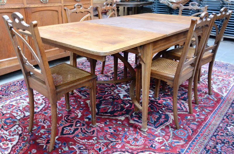 Een art nouveau tafel met zes bijbehorende stoelen van gesculpteerd eikenhout. Tafel met twee verlengbladen.