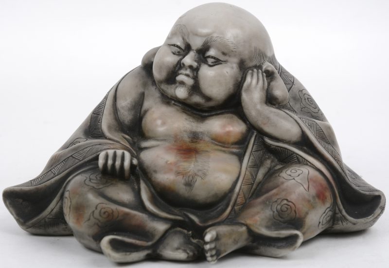 Een zittende Boeddha van gepolierd en gegoten steengoed met een erotische scène onderaan.