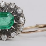 Een 18 karaats wit en geel gouden ring met bijpassende oorbellen en een broche bezet met diamanten met een gezamenlijk gewicht van ± 1 ct. en smaragden met een gezamenlijk gewicht van ± 4 ct.