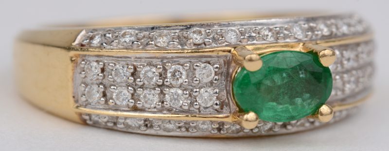 Een 18 karaats wit gouden ring bezet met briljanten met een gezamenlijk gewicht van ± 0,40 ct. en een centrale smaragd van ± 0,30 ct.