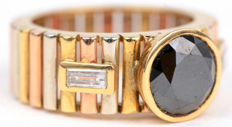 Een 18 karaats driekleurige gouden ring bezet met een centrale zwarte diamant van ± 2 ct. en diamant baguettes met een gezamenlijk gewicht van ± 0,20 ct.
