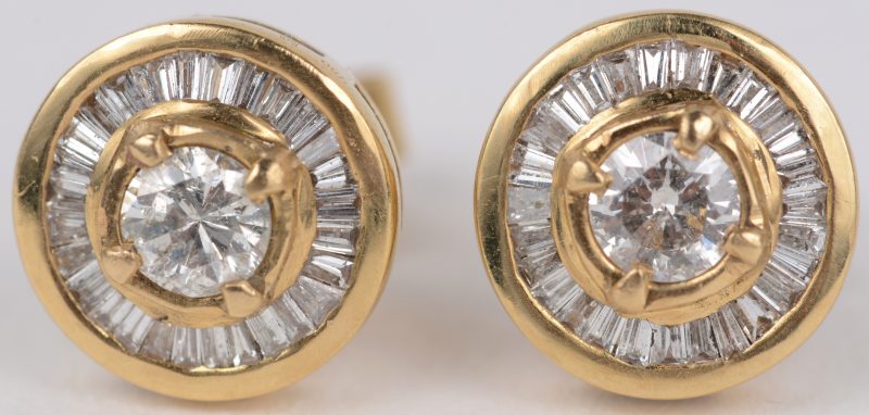 Een paar 18 karaats geel gouden oorbellen bezet met briljanten met een gezamenlijk gewicht van ± 0,40 ct. en diamant baguettes met een gezamenlijk gewicht van ± 0,80 ct.