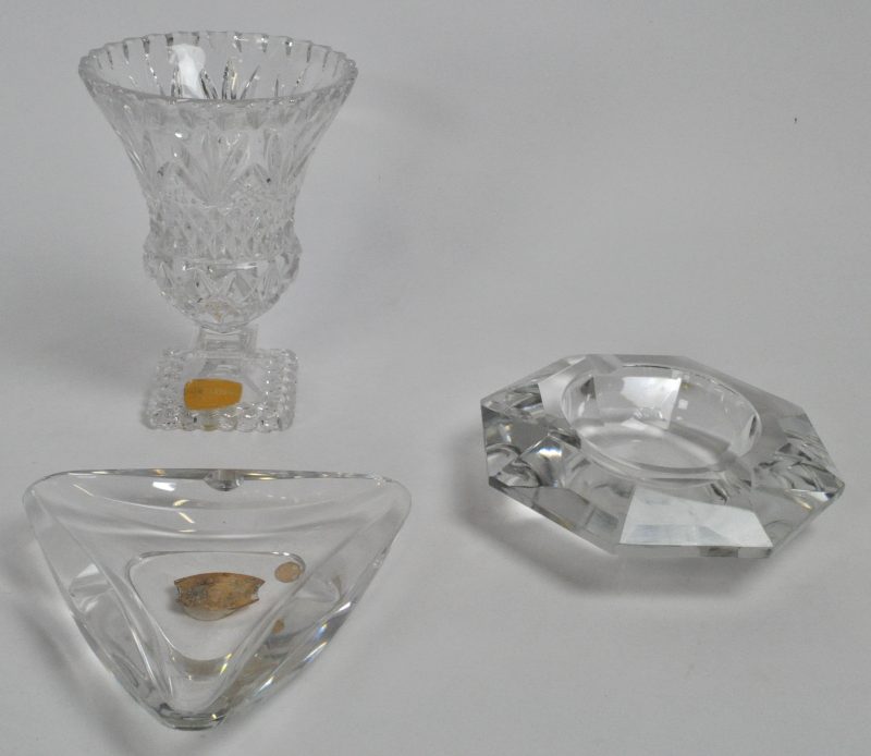 Een lot kleurloos kristal, bestaande uit een siervaasje op voet en twee asbakken, waarvan één gemerkt Val St. Lambert.