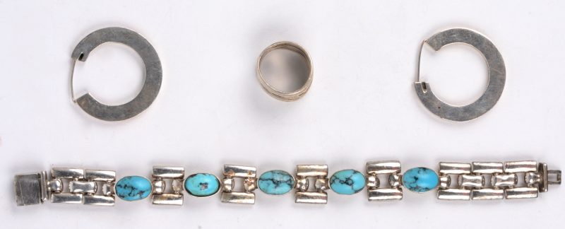 Een zilveren ring, een paar oorbellen en een armband bezet turkoois.