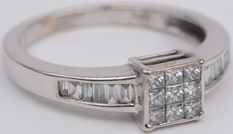 Een 18 karaats wit gouden ring bezet met diamant in princess geslepen met een gezamenlijk gewicht van ± 0,40 ct. en diamant baguettes met een gezamenlijk gewicht van ± 0,40 ct.