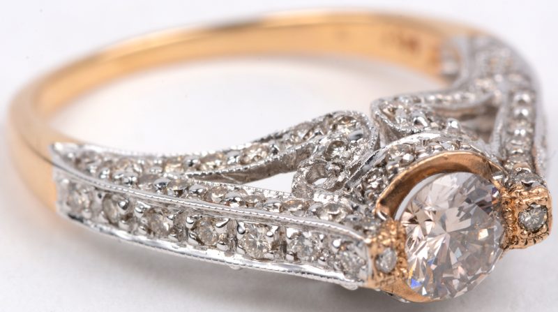 Een 18 karaats wit en geel gouden ring bezet met diamanten met een gezamenlijk gewicht van ± 1 ct. en een centrale diamant van ± 0,50 ct.
