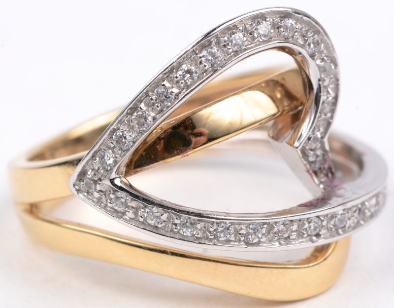 Een 18 karaats wit en geel gouden hartvormige ring bezet met briljanten met een gezamenlijk gewicht van ± 0,35 ct.