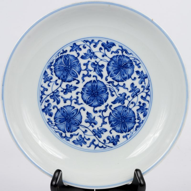 Een diep bord van blauw en wit Chinees porselein met een floraal decor. Onderaan gemerkt.