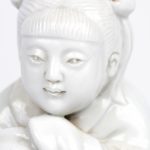 “Kind met bloemenmand op olifant”. Een beeld van monochroom wit porselein naar het blanc de Chine. Achteraan gemerkt.