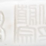 “Kind met bloemenmand op olifant”. Een beeld van monochroom wit porselein naar het blanc de Chine. Achteraan gemerkt.