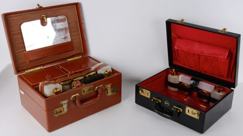 Twee verschillende met leder beklede beauty-cases met twee compartimenten.