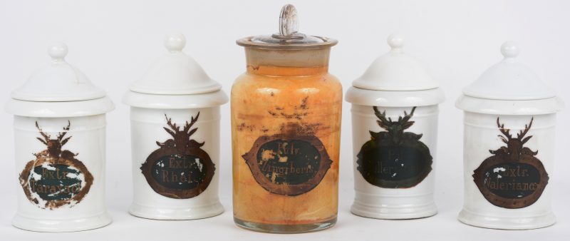 Een set van vier porseleinen en een glazen apothekerspot met fraaie cartouches