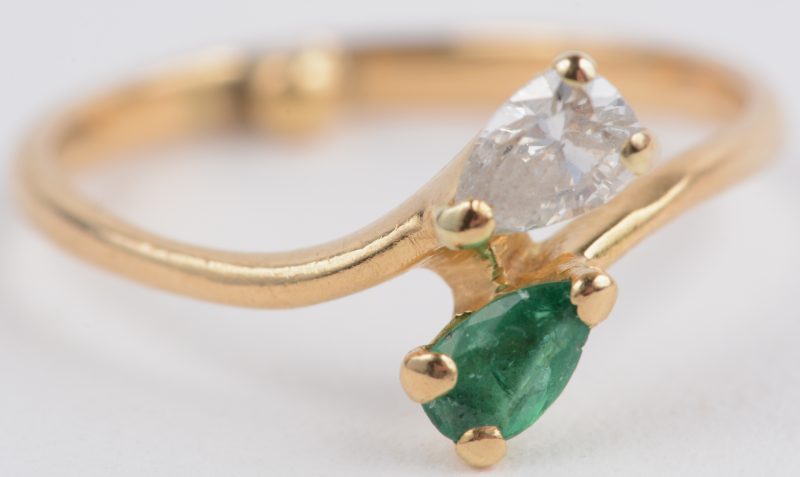 Een 18 karaats geel gouden ring bezet met een diamant en een smaragd van telkens ± 0,15 ct.