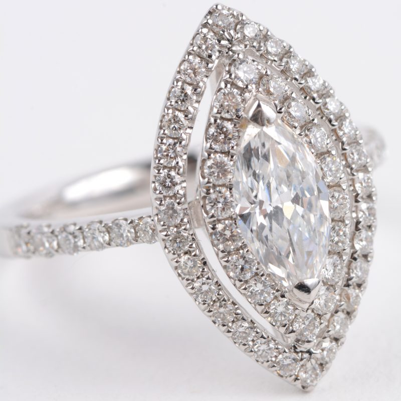 Een 18 karaats wit gouden ring bezet met briljanten met een gezamenlijk gewicht van ± 0,70 ct. en een centrale diamant in markies geslepen van ± 0,70 ct.