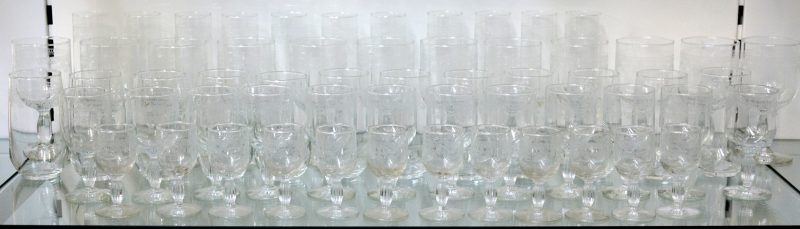 Een glasservies van gegraveerd glas voor twaalf personen, bestaande uit aperitiefglazen, witte- en rodewijnglazen, champagnefluiten en waterglazen. Eén champagnefluit manco.