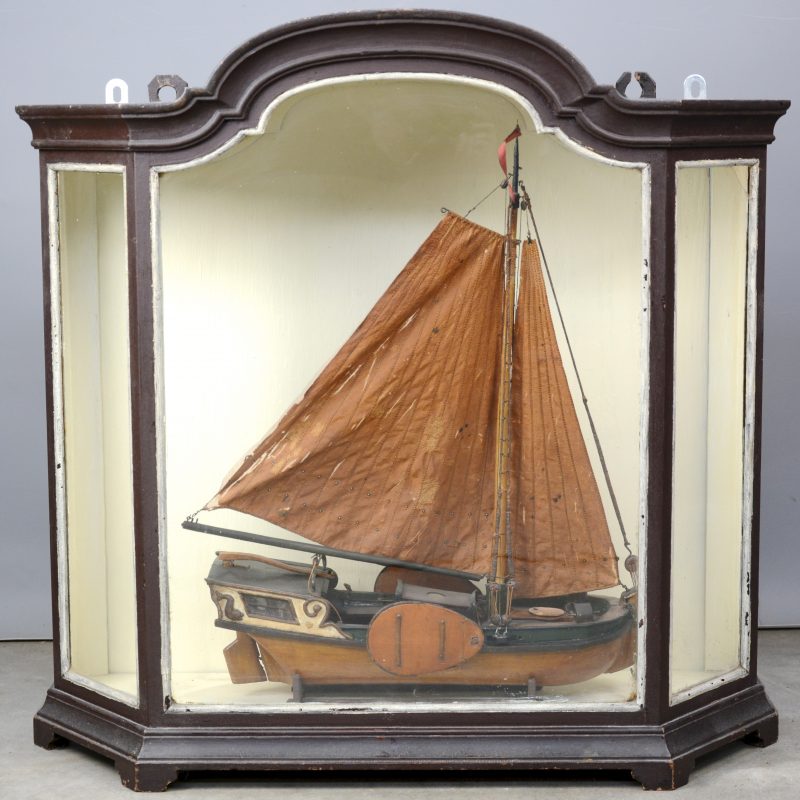 Een oude scheepsmacquette van een tjalk in een XIXe eeuwse presenteervitrine.