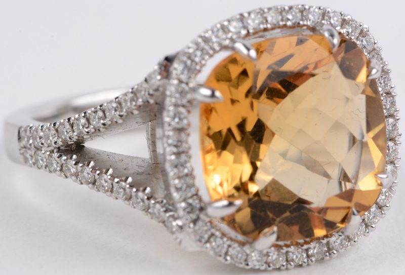 Een 18 karaats wit gouden ring bezet met diamanten met een gezamenlijk gewicht van ± 1 ct. en een centrale gele topaas van ± 10 ct.