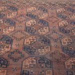 Een antiek handgeknoopt Afghaans wollen tapijt. Slijtage en een enkele gaten.