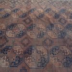 Een antiek handgeknoopt Afghaans wollen tapijt. Slijtage en een enkele gaten.
