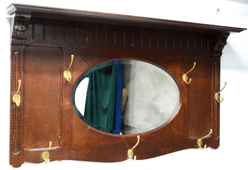 Een wandkapstok met ovale spiegel en zeven haken.