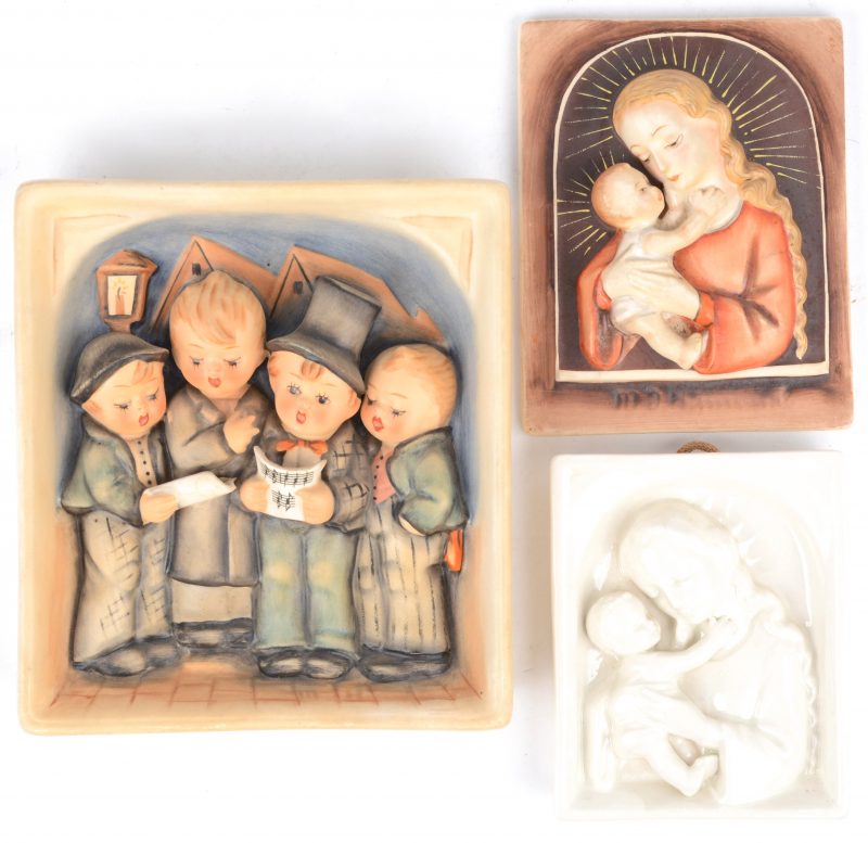Drie plaquettes van porselein, waarbij twee met een afbeelding van Maria met Jezus, resp. polychroom en monochroom wit en één met een decor van straatzangers.