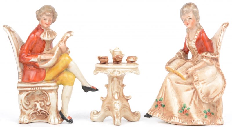 Een groepje van Saksich porselein in de vorm van een lezende dame en een musicerende heer bij een koffietafeltje. Onderaan gemerkt.
