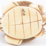 Een netsuké van gebeeldhouwd ivoor met voorstelling van een man op een schildpad. Japans werk, begin XXste eeuw. Onderaan gemerkt.