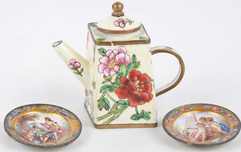 Een paar miniatuurbordjes van geëmailleerd koper, gemonteerd als broche. Wenen, XIXde eeuw (Ø 5 cm)(slijtageplekken aan het verguldsel). En een klein geëmailleerd theepotje met bloemenmotief. Einde XIXde eeuw (H. 8 cm).
