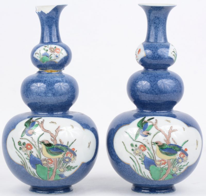 Een paar kalebasvazen met een famille rose decor van vogels op een poederblauwe achtergrond. Chinees werk, XIXde eeuw. Onderaan gemerkt in blauw onder glazuur. Eén vaas erg beschadigd aan de hals, gelijmd en met ontbrekende stukken.