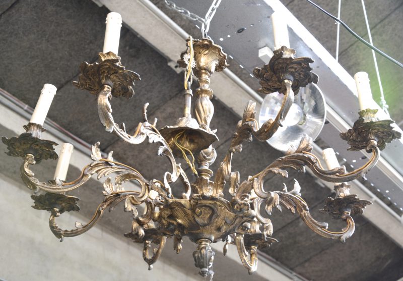 Een bronzen luchter in Lodewijk XV-stijl met acht lichtpunten.