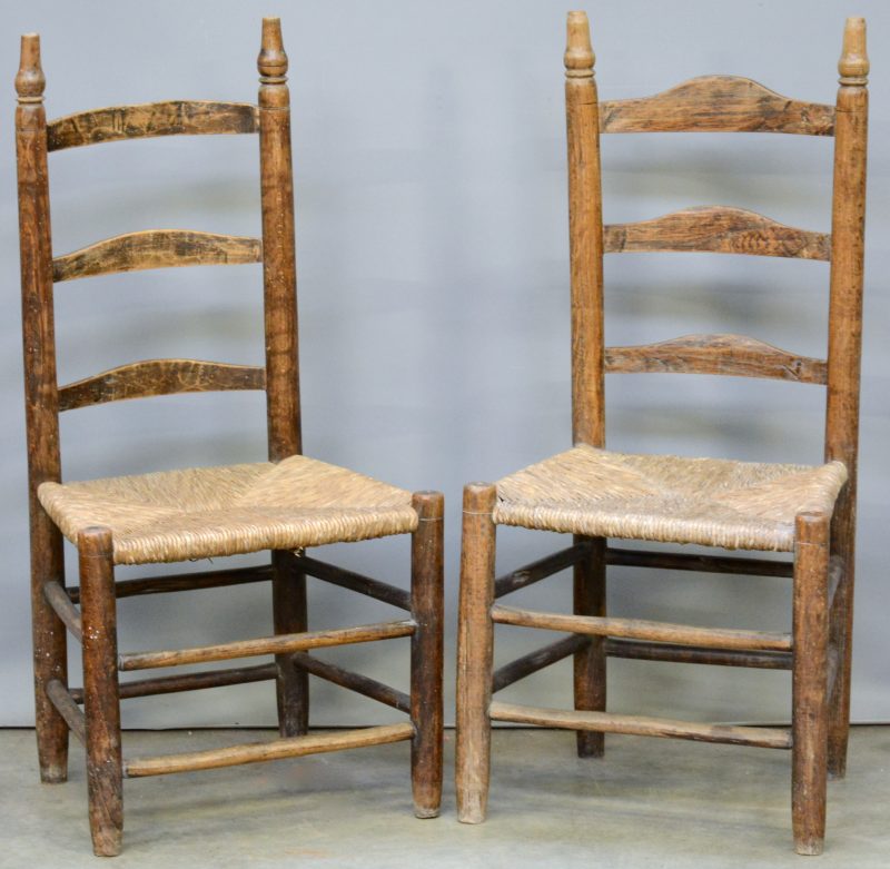 Paar antieke houten kerkstoelen met rieten zit.