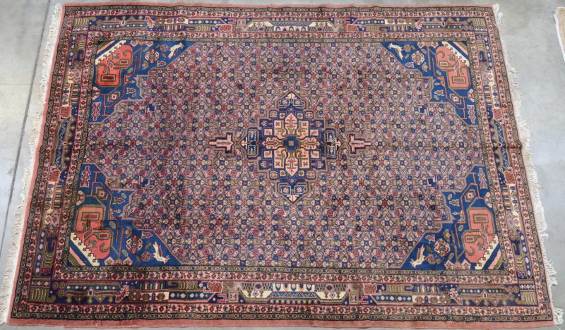 Een handgeknoopt Perzisch wollen tapijt. Zeer lichte verkleuring en slijtage op de hoek.