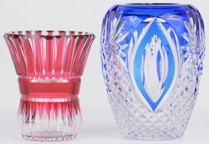 Een eironde vaas van geslepen kleurloos en blauw kristal. We voegen er en klein rood vaasje aan toe. Beide onderaan gemerkt.