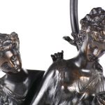 Een lapvoet van donkergepatineerd brons met een classicistische scène van twee dames en een kap van glas in lood.