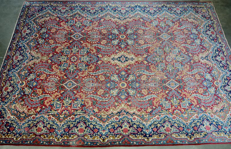 Een antiek handgeknoopt Perzisch tapijt. Slijtage.