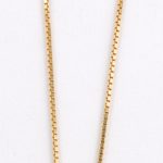 Een 18 karaats geel gouden ketting met hanger bezet met briljanten met een gezamenlijk gewicht van ± 0,20 ct. en robijnen met een gezamenlijk gewicht van ± 1,50 ct.
