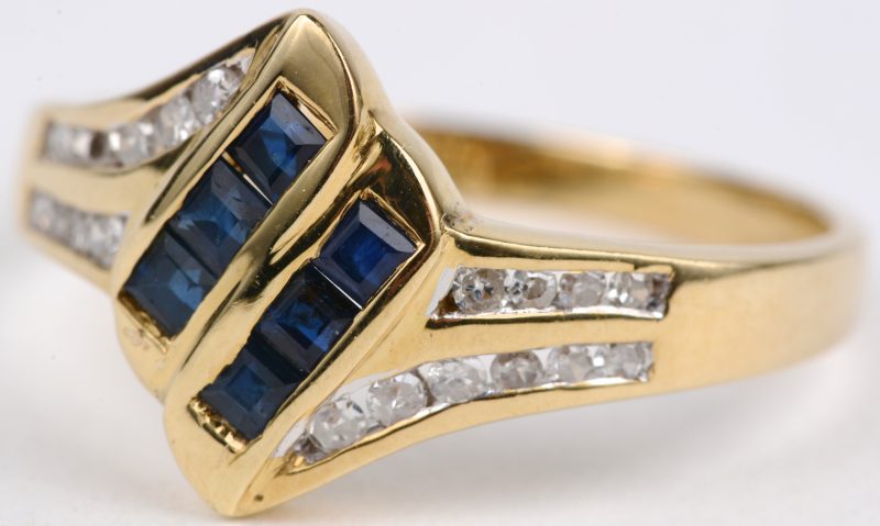 Een 18 karaats geel gouden ring bezet met diamanten met een gezamenlijk gewicht van ± 0,20 ct. en saffier baguettes met een gezamenlijk gewicht van ± 0,30 ct
