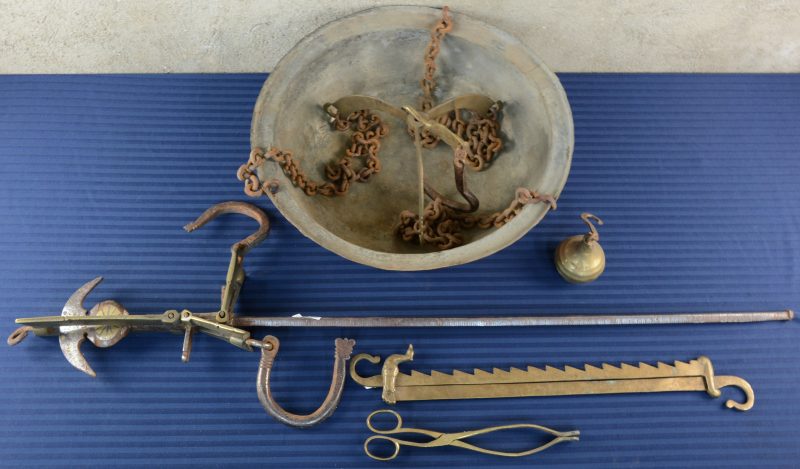 Een koperen ketel met ijzeren kettingen en een groot haardijzer. We voegen er een bronzen haardijzer aan toe, versierd met een duif en een geelkoperen sinteltang.