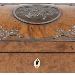 Een wortelhouten doosje versierd met guirlandes van verzilverd metaal. Binnenin muziekdoos en naaigerief. Letsels en manco’s aan schaartje e.d.