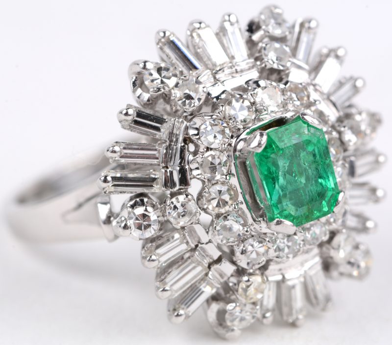 Een 18 karaats wit gouden ring bezet met diamanten en baguettes met een gezamenlijk gewicht van ± 1 ct. en een smaragd baguette van ± 0,70 ct.