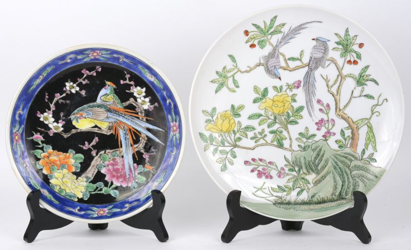 twee borden van Chinees porselein, telkens met een decor van vogels op bloeiende struiken, waarbij één naar het famille noir. Beide onderaan gemerkt.