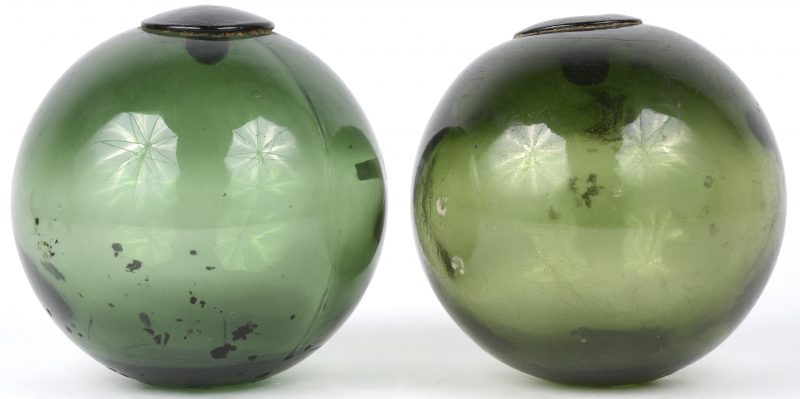 Twee groene glazen drijvers van mondgeblazen glas.
