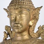 Een bronzen knielende Boeddha met handen in gebedshouding. Bovenaan beschadigd.