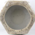 Een zeshoekige vaas van monochroom wit porselein naar het blanc de Chine met een decor van planten en voorwerpen in reliëf.