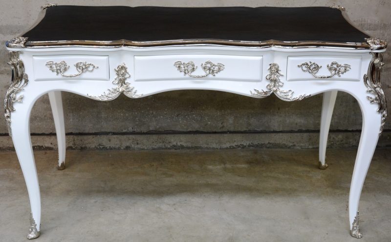 Een witgelakt bureau met drie lden in de gordel en met verchroomde monturen. Lodewijk XV-stijl.