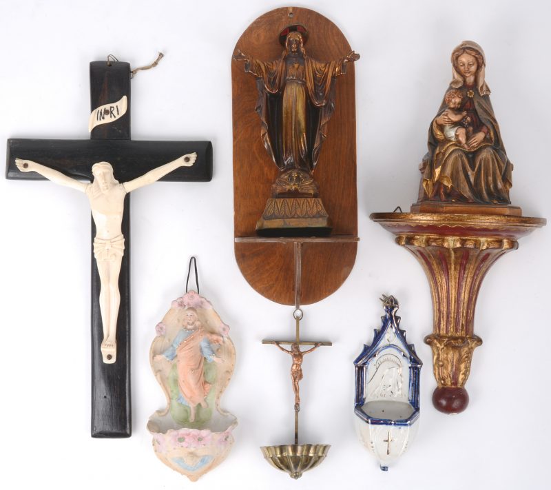 Een lot religieuze voorwerpen, bestaande uit drie verschillende wijwatervaatjes, een ivoren kruisbeeld, een bronzen Christus op console en een Maria met kind van gepolychromeerd hout, eveneens op console.