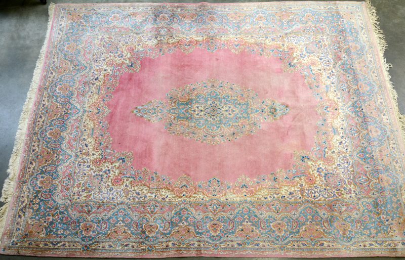 Een handgeknoopt Oosters wollen tapijt. Centraal medaillon op roze veld.