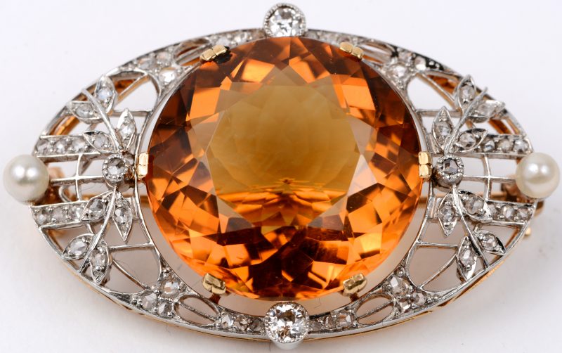 Een 18 karaats wit en geel gouden broche bezet met diamant oude slijp met een gezamenlijk gewicht van ± 0,40 ct. twee parels en een grote barnsteen.